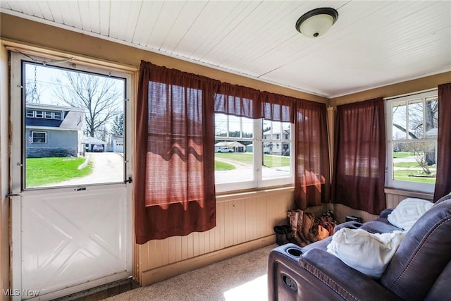 sunroom / solarium with wooden walls, carpet flooring, and a wealth of natural light