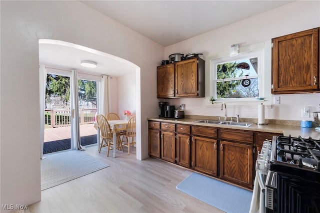 kitchen featuring stainless steel gas range oven, plenty of natural light, arched walkways, and a sink
