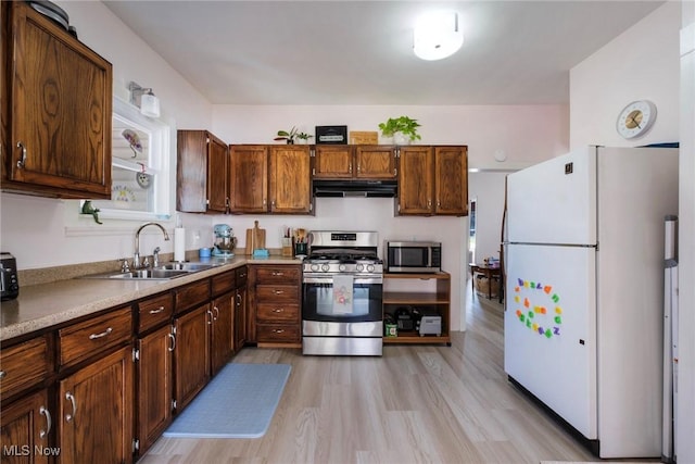 kitchen featuring appliances with stainless steel finishes, light countertops, under cabinet range hood, and a sink