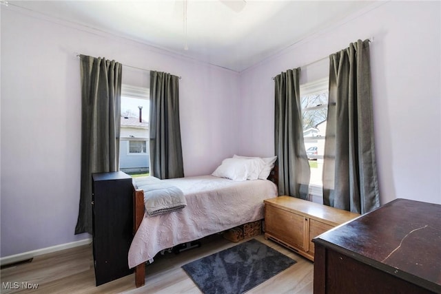 bedroom with crown molding, visible vents, baseboards, and light wood-style floors