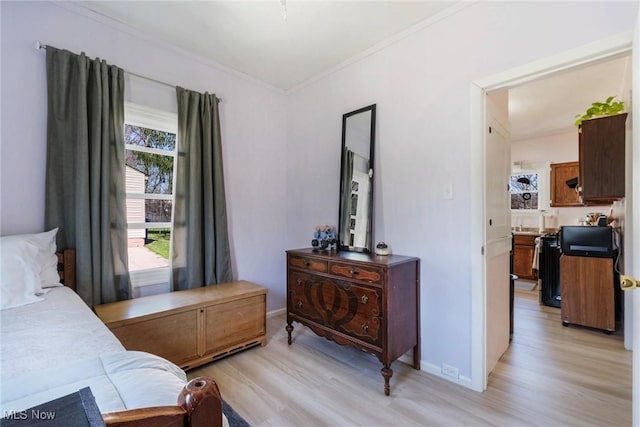 bedroom featuring ornamental molding, light wood finished floors, and baseboards