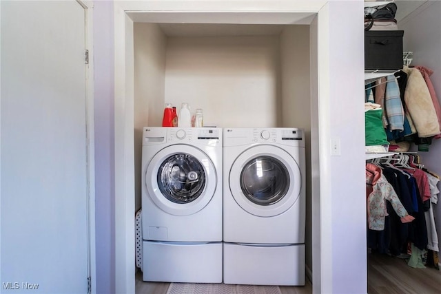 washroom featuring washer and dryer, wood finished floors, and laundry area