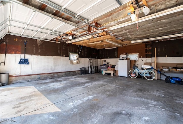 garage featuring freestanding refrigerator and a garage door opener