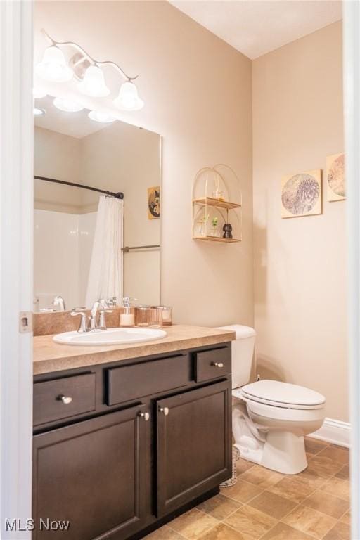 bathroom with baseboards, toilet, and vanity