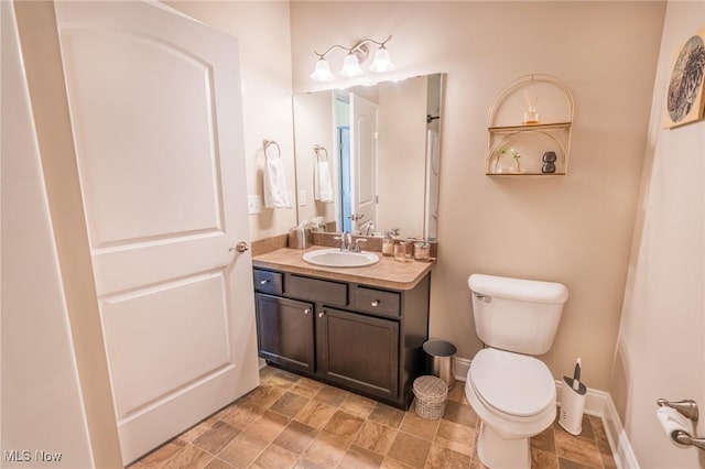 bathroom featuring toilet, stone finish floor, and vanity