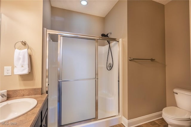 full bathroom with vanity, toilet, a stall shower, and baseboards