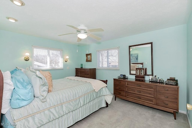 bedroom featuring ceiling fan, light carpet, and multiple windows