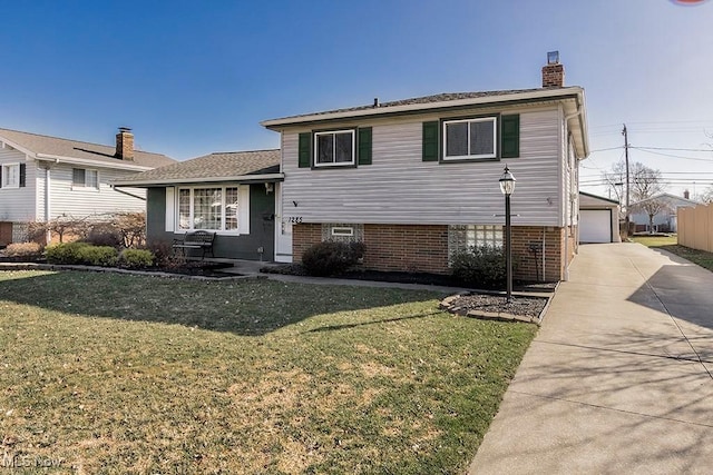 split level home with an outbuilding, a front lawn, brick siding, and a chimney