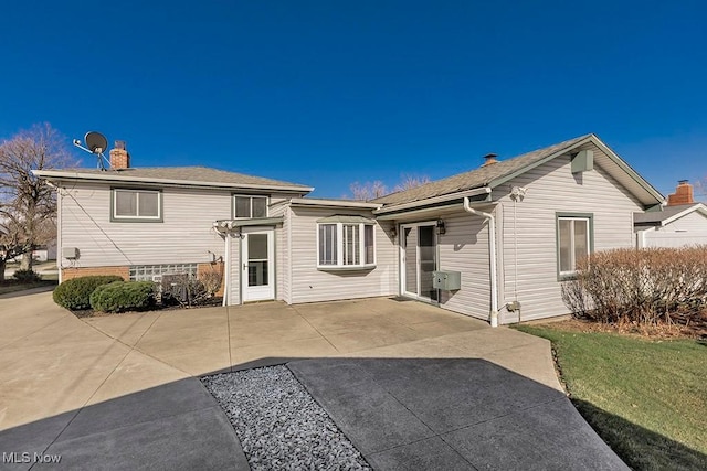 rear view of property featuring a chimney and a patio area