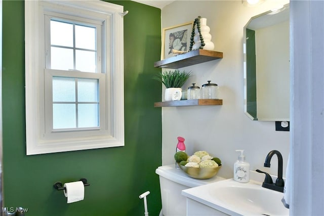 half bathroom with toilet, vanity, and plenty of natural light