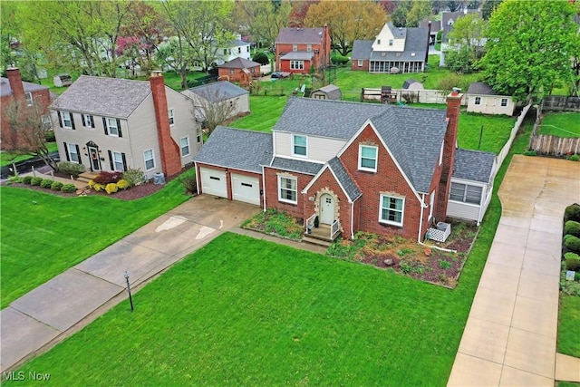 view of front facade with a front lawn, a residential view, brick siding, concrete driveway, and an attached garage