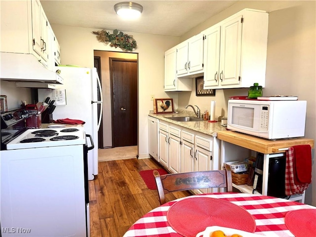 kitchen featuring a sink, under cabinet range hood, white appliances, dark wood-type flooring, and light countertops