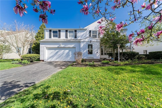 traditional-style home featuring a front yard, aphalt driveway, and a garage