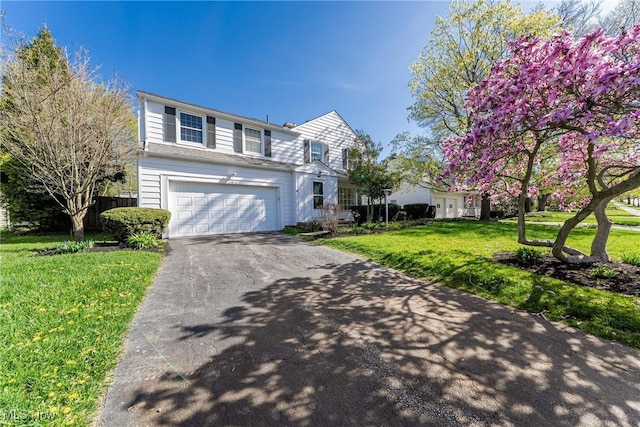 traditional-style home featuring a garage, fence, a front lawn, and driveway