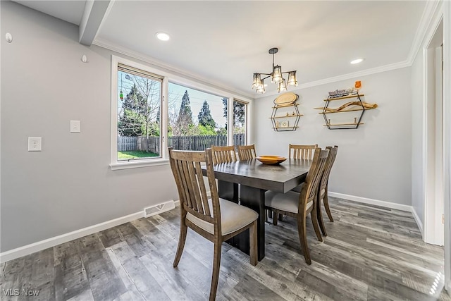 dining area featuring baseboards, visible vents, wood finished floors, and an inviting chandelier