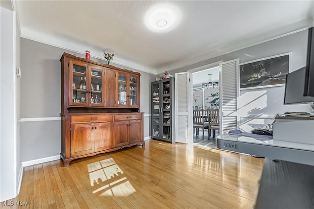 bar featuring a notable chandelier, light wood-style flooring, and baseboards