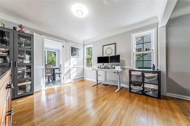 interior space featuring visible vents, crown molding, light wood-style flooring, and baseboards
