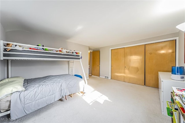 bedroom with a closet, visible vents, and light carpet