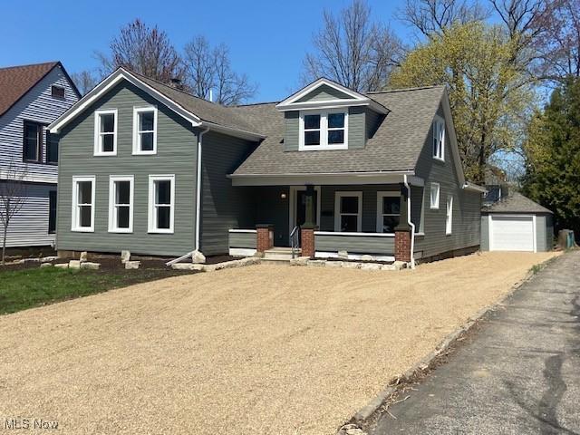 view of front of property featuring an outdoor structure, a detached garage, a porch, and a shingled roof
