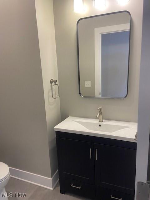 half bath with toilet, vanity, and baseboards