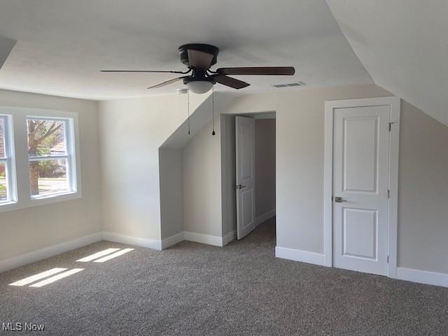 additional living space with baseboards, visible vents, ceiling fan, and carpet