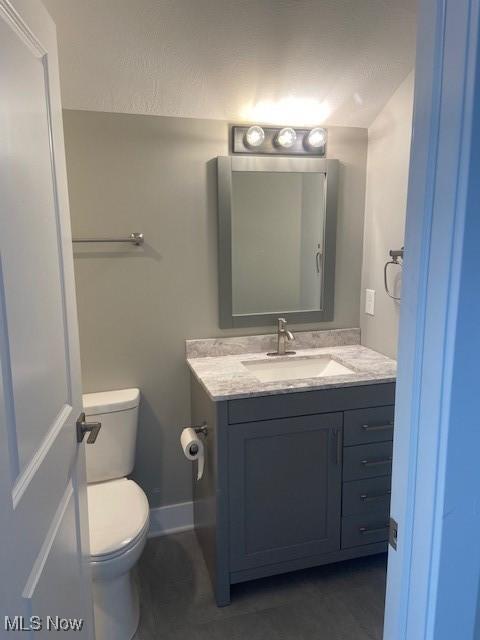 bathroom featuring vanity, toilet, and baseboards
