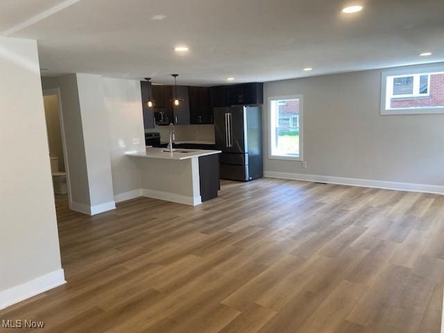 kitchen with a peninsula, appliances with stainless steel finishes, open floor plan, and baseboards