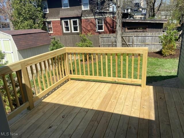 wooden deck featuring a storage shed, an outdoor structure, and a fenced backyard