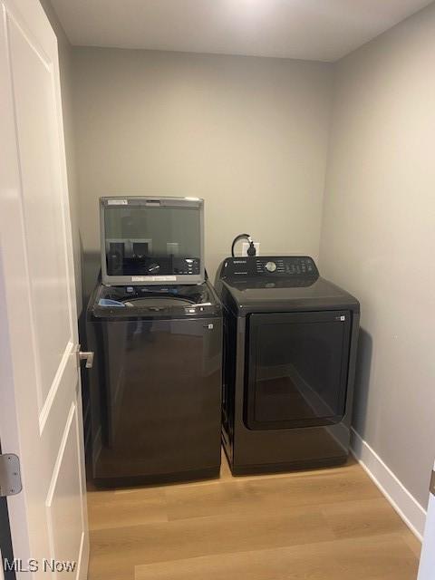 laundry area with separate washer and dryer, light wood finished floors, laundry area, and baseboards