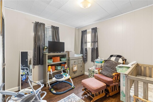 bedroom with crown molding, wood walls, and wood finished floors