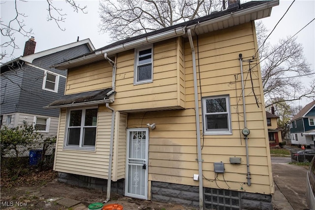rear view of property with a chimney and fence