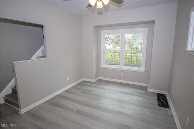 empty room with baseboards, visible vents, wood finished floors, and ceiling fan