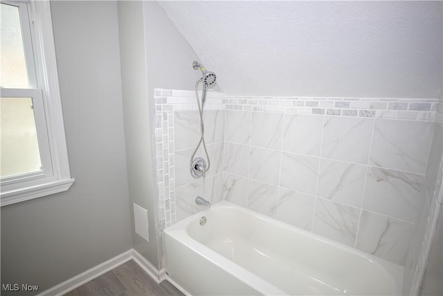full bath featuring baseboards,  shower combination, wood finished floors, and plenty of natural light