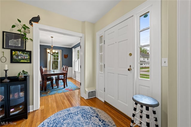 142 Gillett St, Painesville, OH 44077 - entrance foyer with crown molding, an inviting chandelier, baseboards, and light wood-style floors