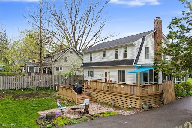 142 Gillett St, Painesville, OH 44077 - rear view of house featuring a deck, an outdoor fire pit, a chimney, fence, and roof with shingles