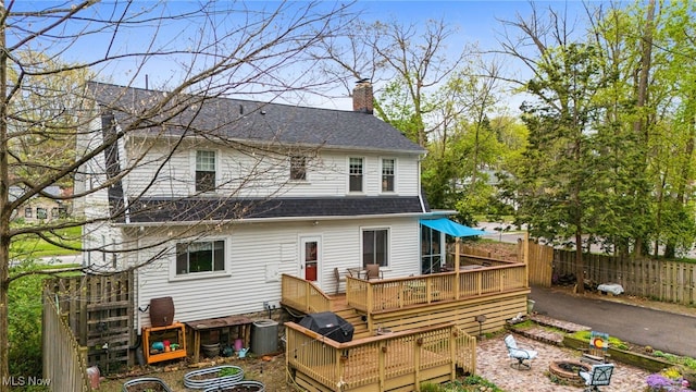 142 Gillett St, Painesville, OH 44077 - rear view of house featuring a wooden deck, a shingled roof, central AC, a chimney, and fence