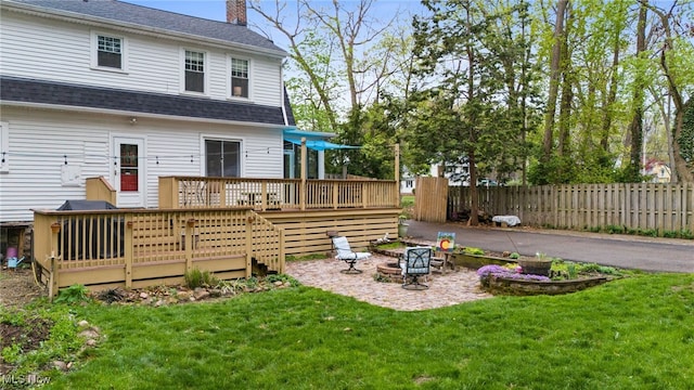142 Gillett St, Painesville, OH 44077 - back of property featuring a wooden deck, a chimney, an outdoor fire pit, fence, and a yard