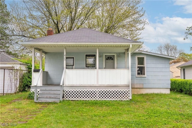 view of front facade featuring a porch, a front yard, a shingled roof, and a chimney
