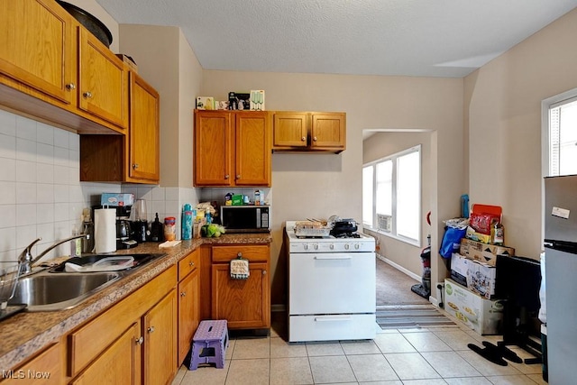 kitchen with stainless steel microwave, a sink, a healthy amount of sunlight, and gas range gas stove