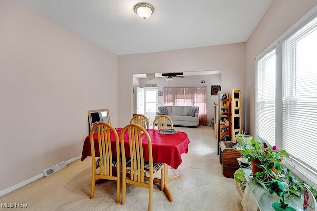 carpeted dining room featuring visible vents, a ceiling fan, and baseboards