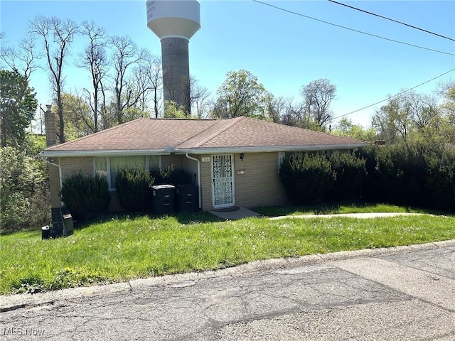 single story home with a chimney, a front yard, and brick siding