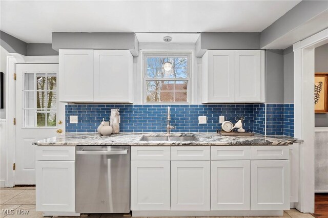 kitchen featuring light stone counters, white cabinetry, tasteful backsplash, stainless steel dishwasher, and a sink