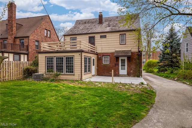 back of house with a patio, a chimney, fence, a yard, and brick siding
