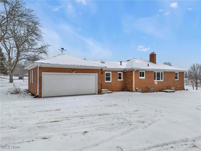 340 53rd St SW, Canton, OH 44706 - snow covered rear of property featuring a chimney, brick siding, and a garage