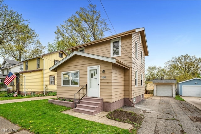 traditional-style house featuring an outbuilding, a detached garage, a front yard, and entry steps