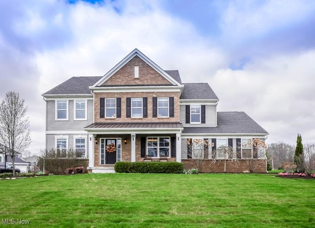 view of front facade featuring brick siding, a porch, a front lawn, and a standing seam roof