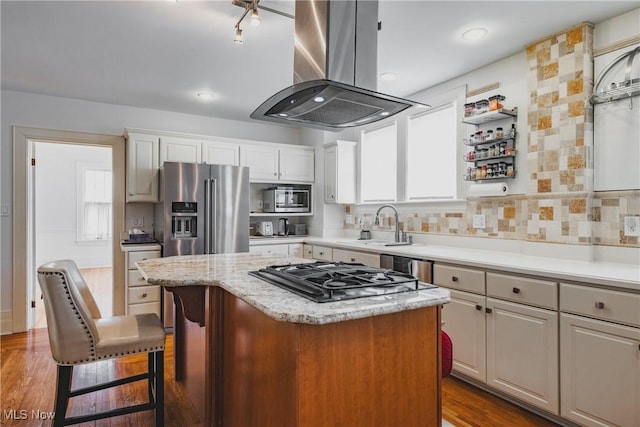 kitchen with a center island, island range hood, appliances with stainless steel finishes, and plenty of natural light