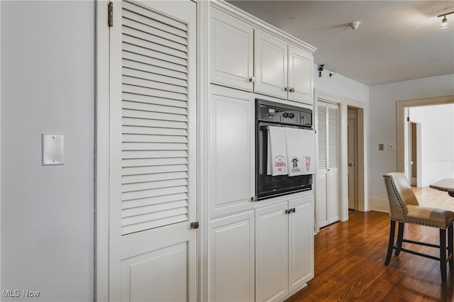 kitchen with white cabinetry, baseboards, dark wood finished floors, and black oven