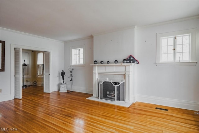unfurnished living room with baseboards, ornamental molding, wood finished floors, and a fireplace