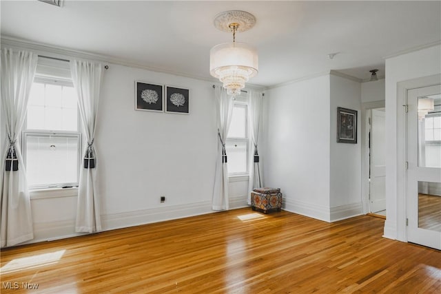 unfurnished dining area with a chandelier, crown molding, light wood finished floors, and baseboards